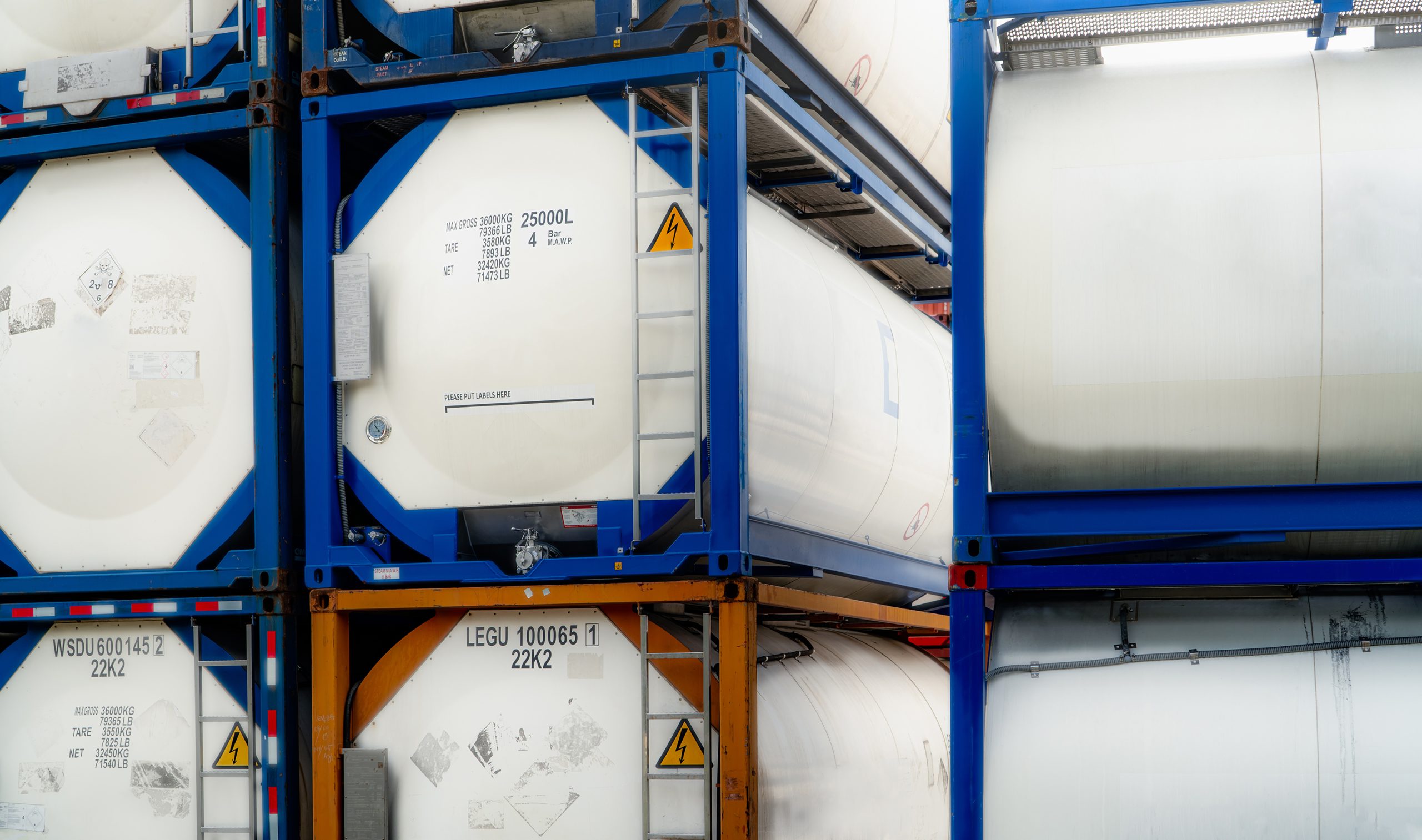 Chemical tank containers stacked in a warehouse.