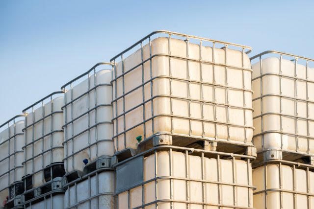 White ibc container stacked in outdoor stock yard of factory, white plastic chemical tanks.